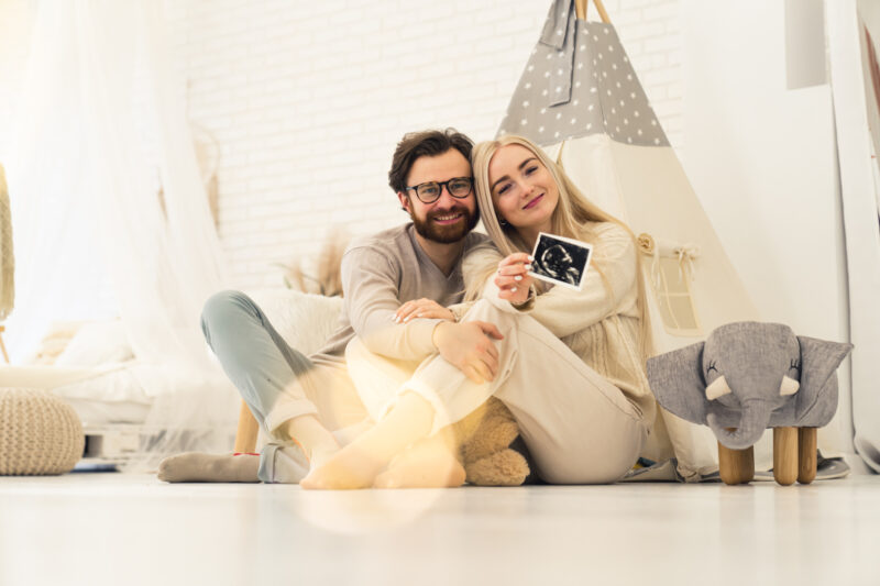 Happy couple after fertility treatment holding a sonogram image of the baby